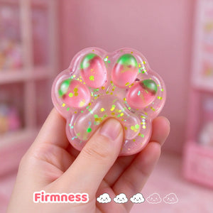 Hand holding the translucent pink cat paw squishy to show its size.