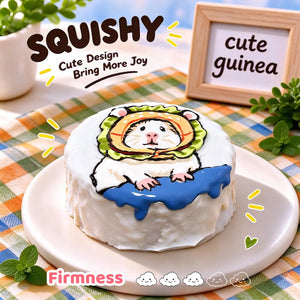 Guinea pig squishy side view, round white squishy with hand-painted guinea pig in green orange hood and blue dripping detail, soft glossy silicone texture, thick cake-like side profile, green orange checkered table setting, wooden "cute guinea" sign in background