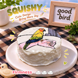 Parrot squishy side view, round white squishy with hand-painted colorful parrot perched on a hand, soft glossy silicone texture, thick cake-like side profile, brown beige checkered table setting, wooden "good bird" sign and bird seed in background