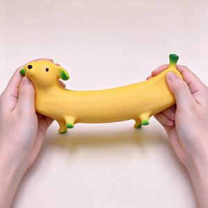 A hand holding a long yellow banana-shaped dog squishy to show its size.