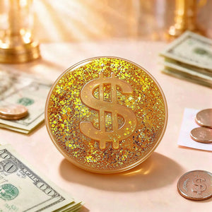Gold dollar-sign coin squishy displayed on a warm golden surface beside banknotes and coins.