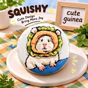 Guinea pig squishy product photo, round white squishy with hand-painted cute guinea pig wearing a green and orange hood, sitting on blue surface, pet dessert-style scene, green orange checkered tablecloth, wooden "cute guinea" sign, plants and playful yellow accents