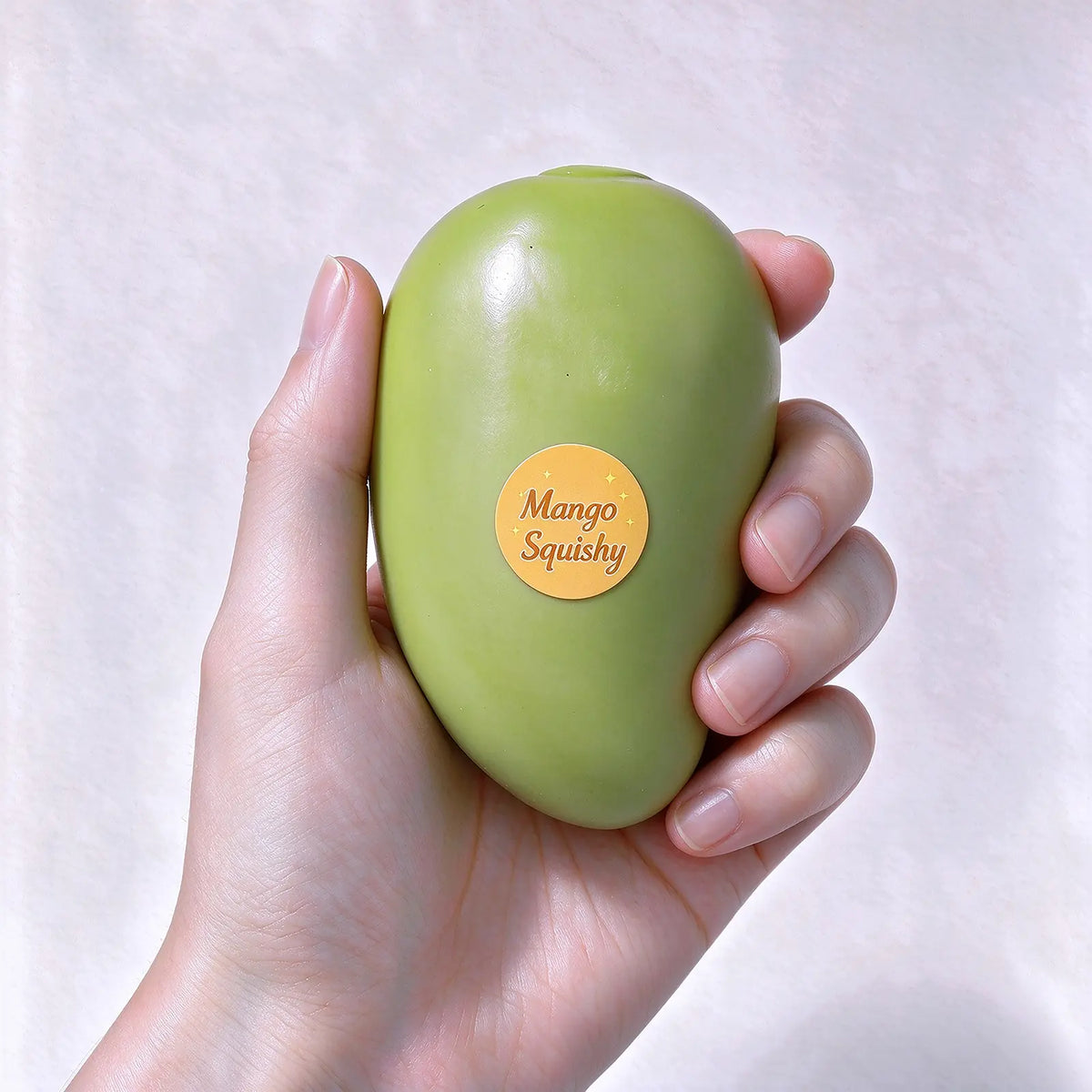 A hand holding a smooth green mango-shaped squishy toy.