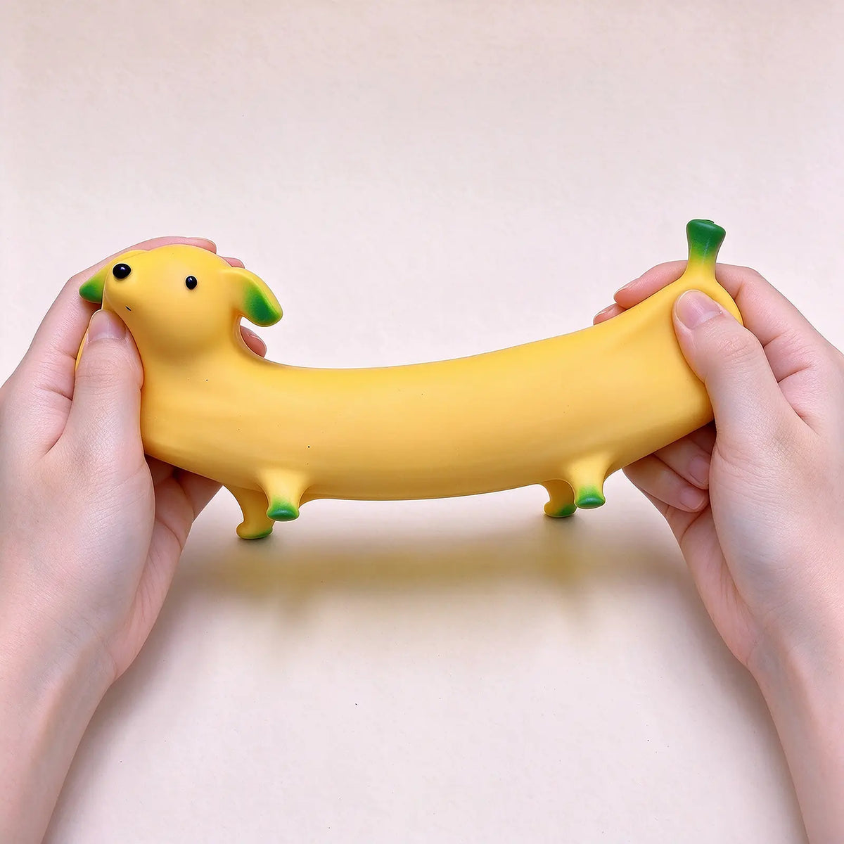 A hand holding a long yellow banana-shaped dog squishy to show its size.