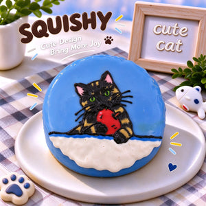 Hand-painted Tortoiseshell Cat squishy toy, cute Tortie cat portrait holding red fish on soft round fidget toy, blue glossy surface on display plate